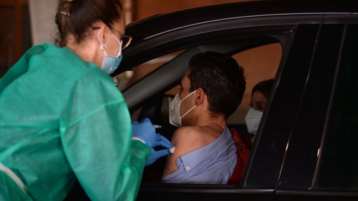 عامل صحي يعطي جرعة من لقاح أسترازينيكا / أكسفورد لرجل في سيارة في مركز تطعيم ضد فيروس كورونا في ملعب نويفو كولومبينو، إسبانيا، 24 مارس 2021