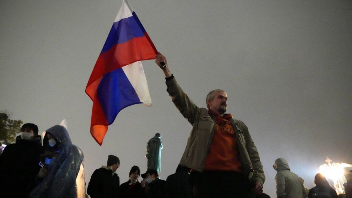 FILE - In this Sept. 20, 2021 file photo, a demonstrator holds a Russian national flag during a protest against the results of the Parliamentary election in Moscow, Russia. 