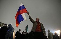 FILE - In this Sept. 20, 2021 file photo, a demonstrator holds a Russian national flag during a protest against the results of the Parliamentary election in Moscow, Russia.