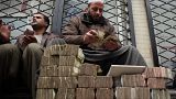 An Afghan money changer, right, counts a pile of currency. Cryptocurrencies, on the other hand, have been a financial lifeline for many Afghans 