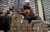 An Afghan money changer, right, counts a pile of currency. Cryptocurrencies, on the other hand, have been a financial lifeline for many Afghans