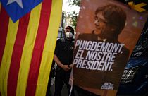 A mossos d'esquadra police officer stands behind a banner and a Catalonia independence flag with the image of former Catalan leader Carles Puigdemont.