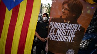 A mossos d'esquadra police officer stands behind a banner and a Catalonia independence flag with the image of former Catalan leader Carles Puigdemont.