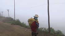 An indigenous woman walking amid the fog.