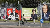 People walk and drive past election posters of the three chancellor candidates in Gelsenkirchen, Germany, Sept. 23, 2021.