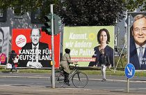People walk and drive past election posters of the three chancellor candidates in Gelsenkirchen, Germany, Sept. 23, 2021. 
