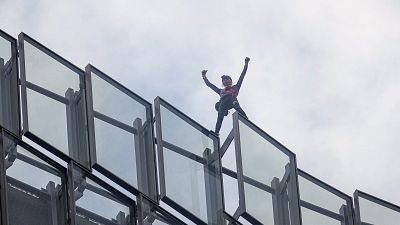 French urban climber Alain Robert raises his arms as he finished to climb the the 160-meters Alto tower at La Defense business district.