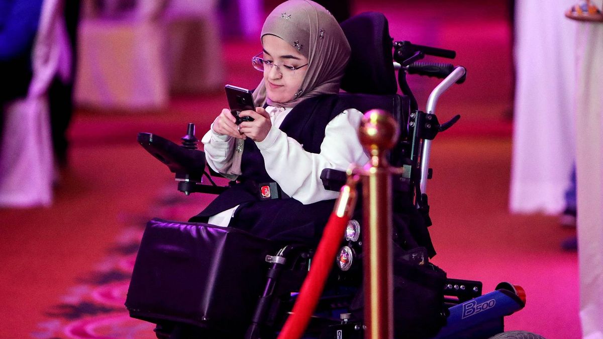 فتاة كويتية من ذوي الاحتياجات الخاصة تنظر إلى هاتفها الخلوي خلال نشاط لذوي الاحتياجات الخاصة في مدينة الكويت، 28 أبريل 2018.