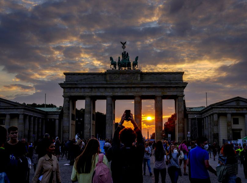 گردشگران در غروب خورشید پشت دروازه براندنبورگ در برلین، عکس می‌گیرند