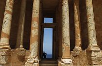 رجل ليبي يتكئ على جزء من المدرج الروماني في موقع صبراتة الأثري في ليبيا