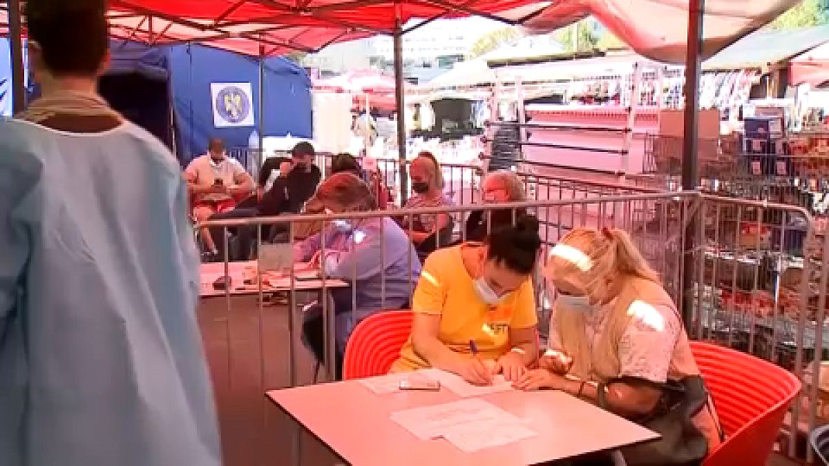 People filling in documents prior to vaccination in a Bucharest square