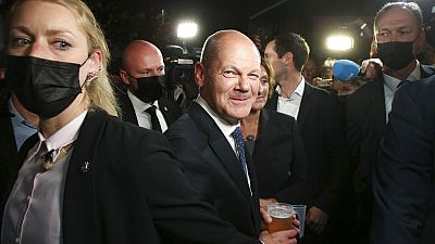 Olaf Scholz, center, Finance Minister and SPD candidate for Chancellor, drinks a beer as he leaves the election party at Willy Brandt House in Berlin