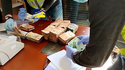 Agentes cuentan el dinero en metálico incautado a los detenidos en España