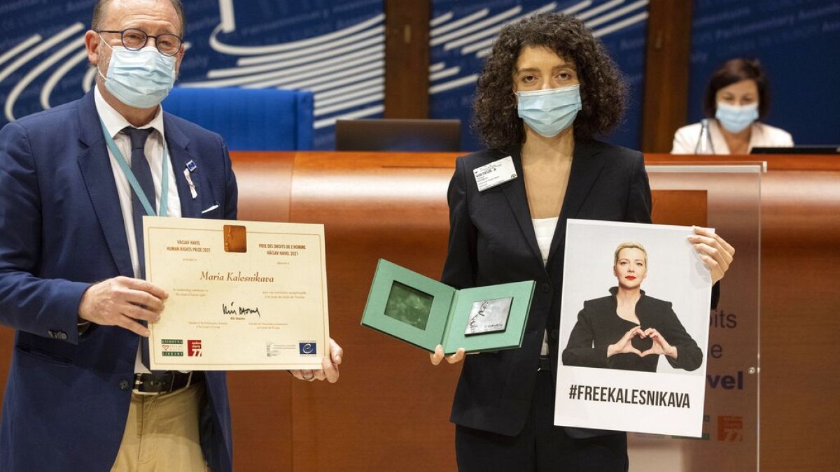 Parliamentary Assembly Rik Daems, left, holds a diploma while Tatiana Khomich holds a poster of jailed Belarus civil rights activist Maria Kalesnikava.