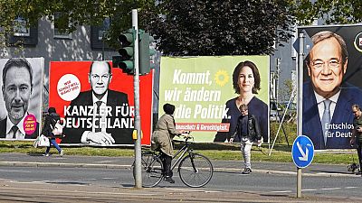 People walk and drive past election posters of the three chancellor candidates and and Christian Lindner, German Liberals (FDP) at a street