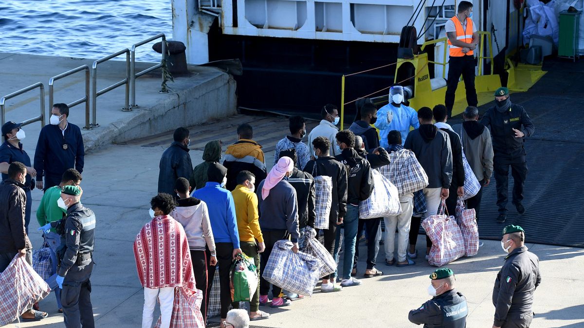 Migrants queue before boarding the GNV Azzurra ship after being transferred from the migrant centre on the Sicilian island of Lampedusa, May 13, 2021. 