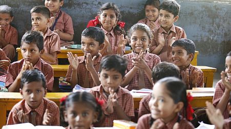A group of children smile as they learn in a classroom.