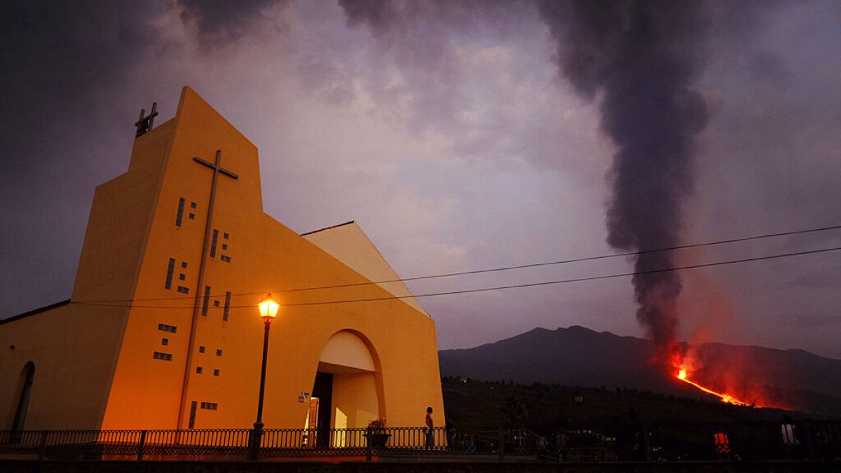 Una persona contempla la erupción del volcán Cumbre Vieja desde la puerta de una Iglesia en la isla española de La Palma