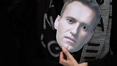 A mask of Russian opposition leader Alexei Navalny is held at a rally in Berlin.