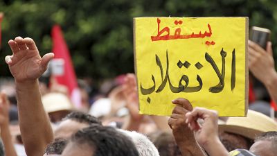 متظاهر يحمل لافتة  كتب عليها "يسقط الانقلاب" خلال مظاهرة ضد الرئيس التونسي قيس سعيد في العاصمة تونس الأحد 26 أيلول/ سبتمبر 2021