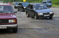 Cars drive over a pothole along a road near Kiev May 16, 2013.