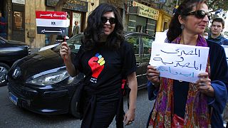 امرأة مصرية تحمل لافتة باللغة العربية كتب عليها: "رجل وامرأة مصريان في يد واحدة" في ميدان التحرير، وسط القاهرة للاحتفال باليوم العالمي للمرأة، مصر، 8 مارس 2011