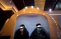 Attendees wearing face masks to protect against the coronavirus ride in a virtual reality simulator at the PT Expo in Beijing.