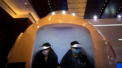 Attendees wearing face masks to protect against the coronavirus ride in a virtual reality simulator at the PT Expo in Beijing.