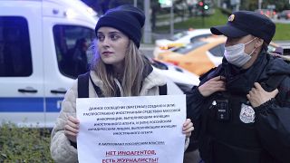 A police officer detains a journalist holding a banner that reads: "There are no foreign agents, there are journalists," in Moscow, Russia, Sept. 8, 2021.