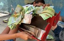 Niños juegan en la calle con bolívares