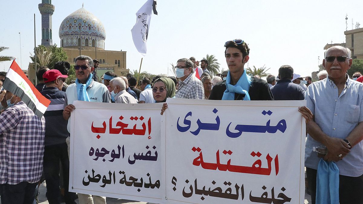عراقيون يحملون لافتات أثناء مظاهرة في ساحة الفردوس وسط بغداد في 1 تشرين الأول 2021.