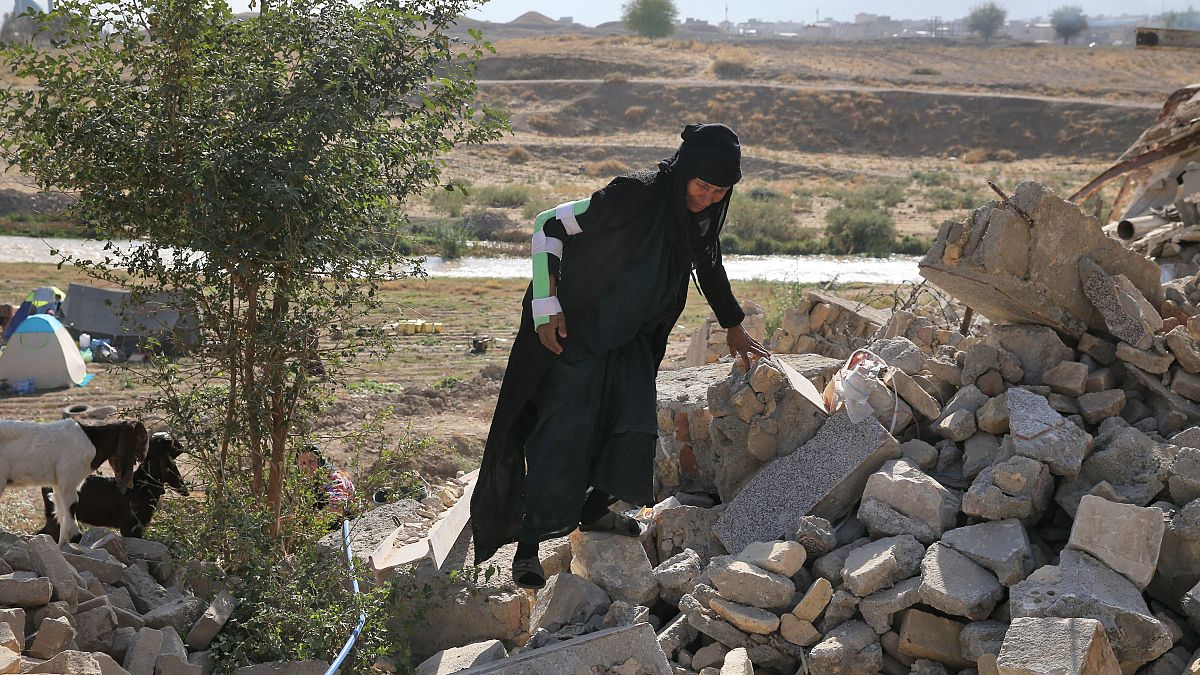 امرأة تمشى على أنقاض بيتها المهدم بسبب الزلزال في سربول الذهب غربي إيران. 2017/11/15