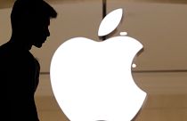 A silhouette of a man standing in front of an Apple store