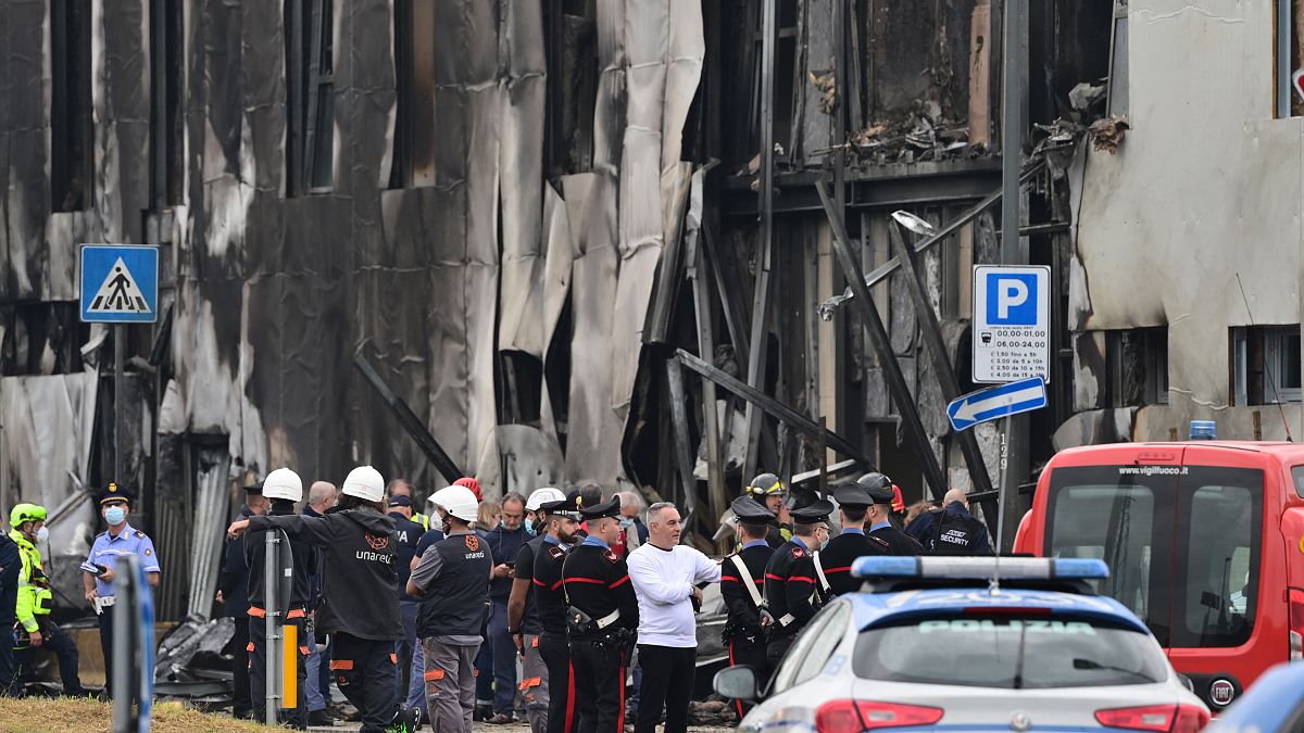 Police and rescue teams stand outside an apparently vacant office building where a small plane crashed in the Milan suburb of San Donato, October 3, 2021.