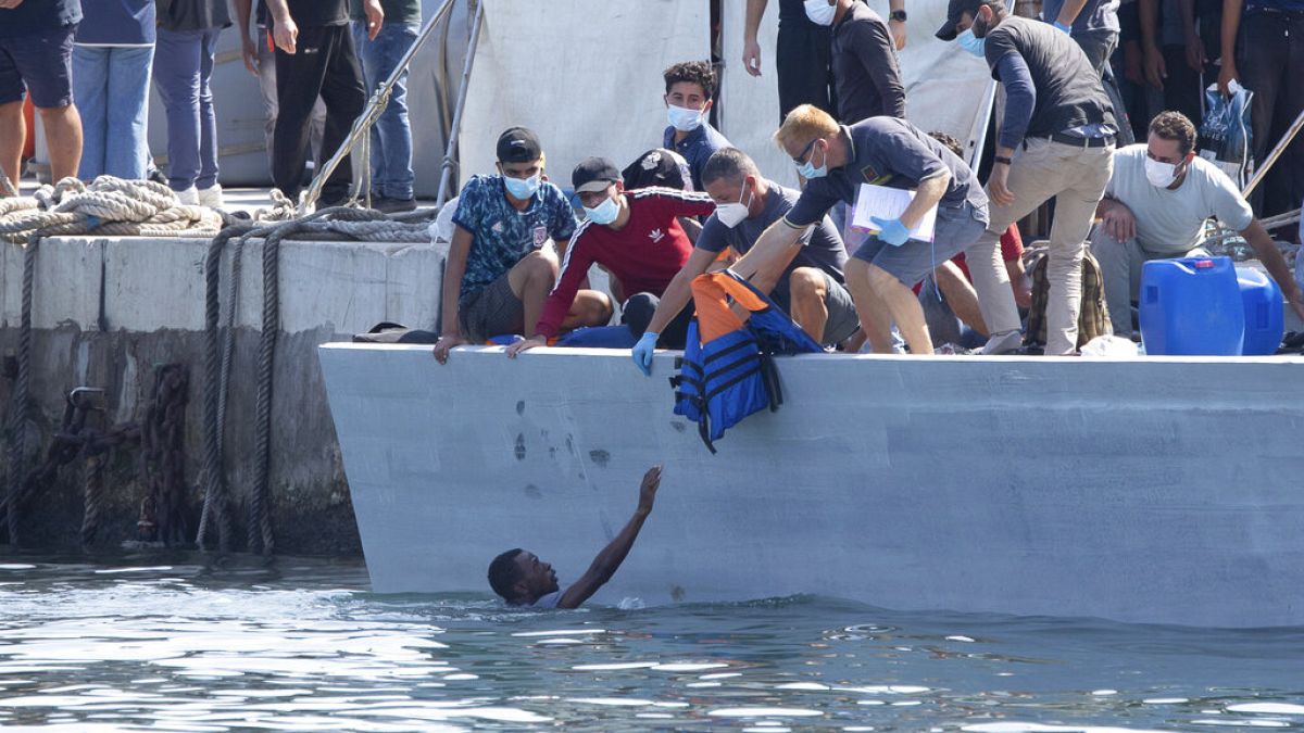 Un homme demande de l'aide, sur l'île italienne de Lampedusa, Italie, le 3 octobre 2021