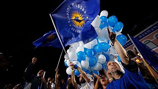 Georgian Dream party supporters cheer, wave flags and hold up balloons.