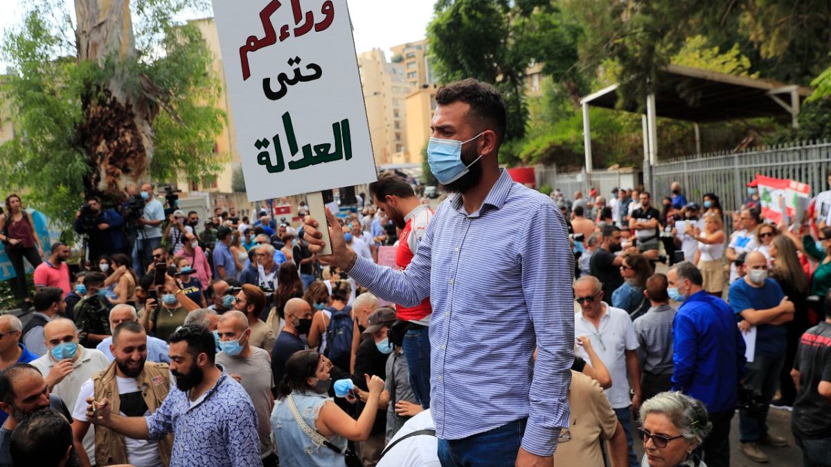 متظاهر يحمل لافتة خارج مبنى المحكمة خلال مظاهرة تضامن مع القاضي طارق بيطار في بيروت، لبنان.