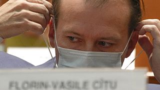 Romanian Prime Minister Florin Citu adjusts his mask ahead of a no confidence vote in Romania's parliament in Bucharest, Romania, Tuesday, Oct. 5, 2021. 