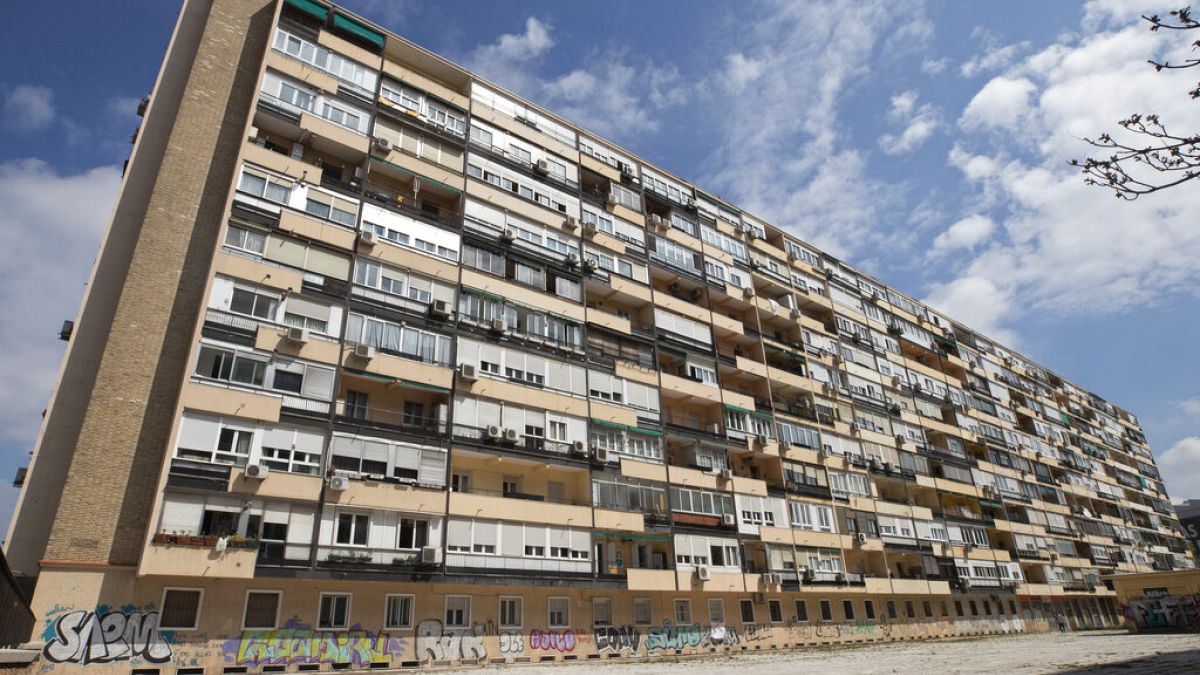 En esta foto de archivo del 8 de abril de 2020, un hombre camina frente a un gran bloque de apartamentos en Madrid, España
