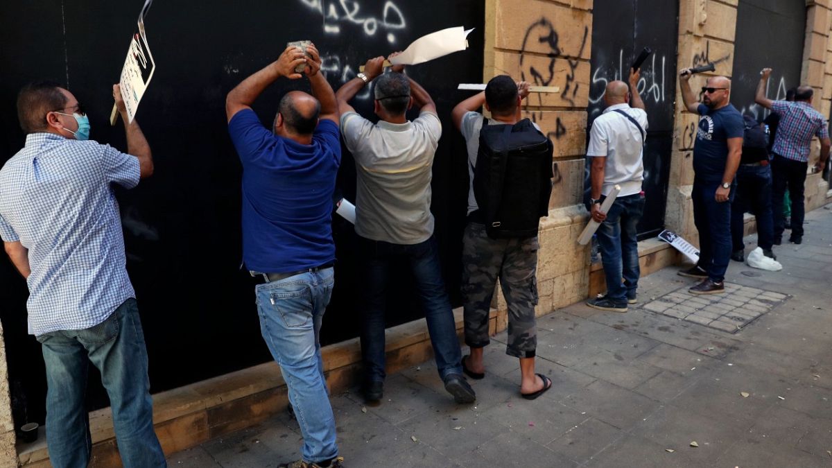 مودعون يدقون على الجدران المعدنية لأحد البنوك خلال احتجاج في بيروت، الأربعاء 6 أكتوبر 2021
