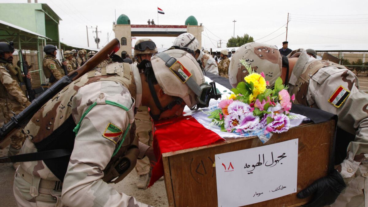 صورة من الارشيف - جنود عراقيون يقبلون نعشاً يحمل رفات جندي عراقي عند المعبر الحدودي العراقي الإيراني في الشلامجة، العراق