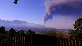 El humo se eleva en el horizonte mientras la lava fluye desde un volcán en la isla canaria de La Palma, España, el miércoles 6 de octubre de 2021
