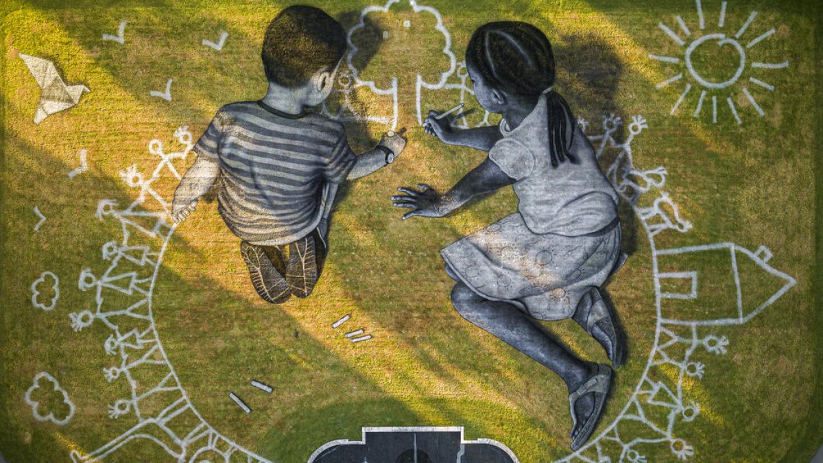 A francia művész, Saype 6000 nm-es tájrajzra, melyen két kisgyerek rajzol - az alkotást az ENSZ genfi székhelye mellett készítették el 2020-ban