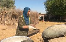 Qahwa, a Syrian mother of eight, is baking the traditional tannour bread.