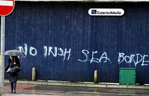 A woman walks past past graffiti with the words 'No Irish Sea Border' in Belfast city centre, Northern Ireland, Wednesday, Feb. 3, 2021.