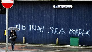 A woman walks past past graffiti with the words 'No Irish Sea Border' in Belfast city centre, Northern Ireland, Wednesday, Feb. 3, 2021.