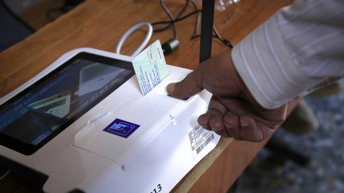 Un uomo fornisce la sua impronta digitale prima del voto, in un seggio elettorale a Baghdad, Iraq