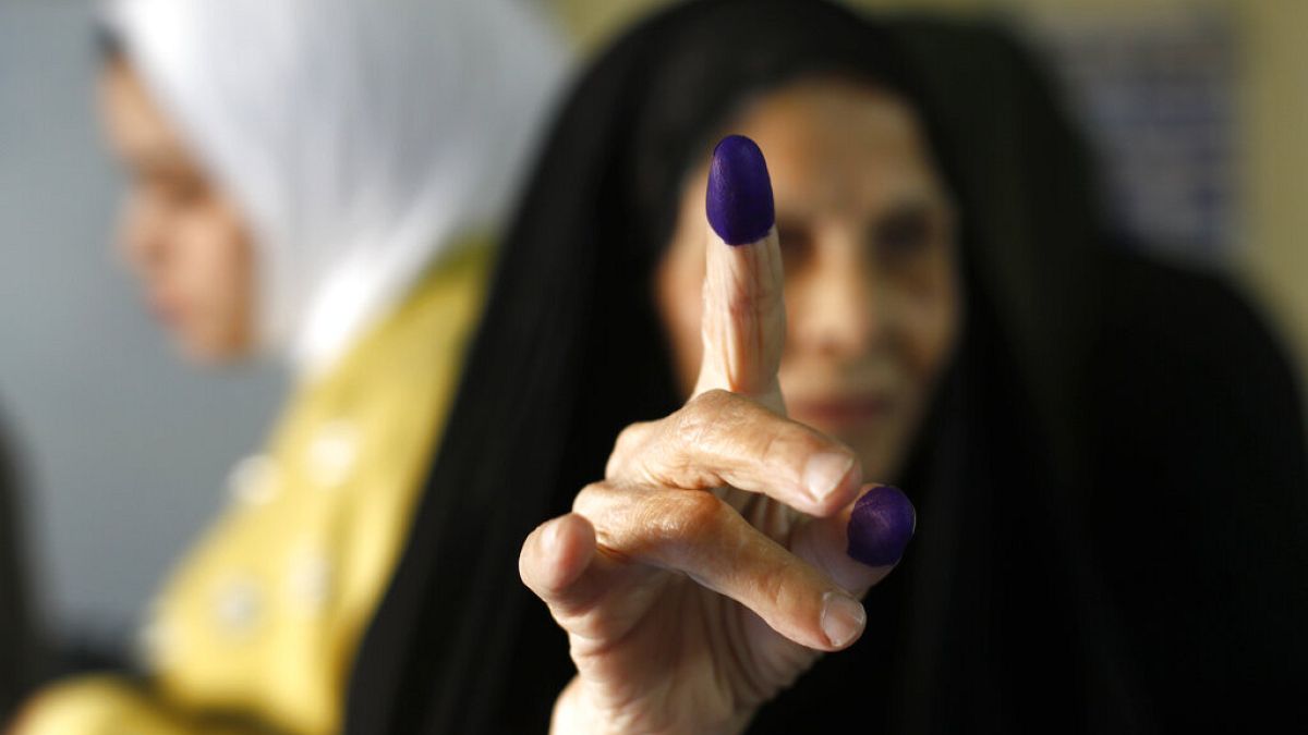 An Iraqi elderly woman shows her ink-stained finger after casting her vote inside a polling station in the country's parliamentary elections in Baghdad, Iraq, Sunday, Oct. 10,