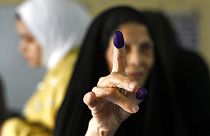 An Iraqi elderly woman shows her ink-stained finger after casting her vote inside a polling station in the country's parliamentary elections in Baghdad, Iraq, Sunday, Oct. 10,
