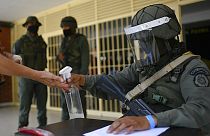 Un soldado echa desinfectante en las manos de un participante en el simulacro electoral en El Valle, Caracas